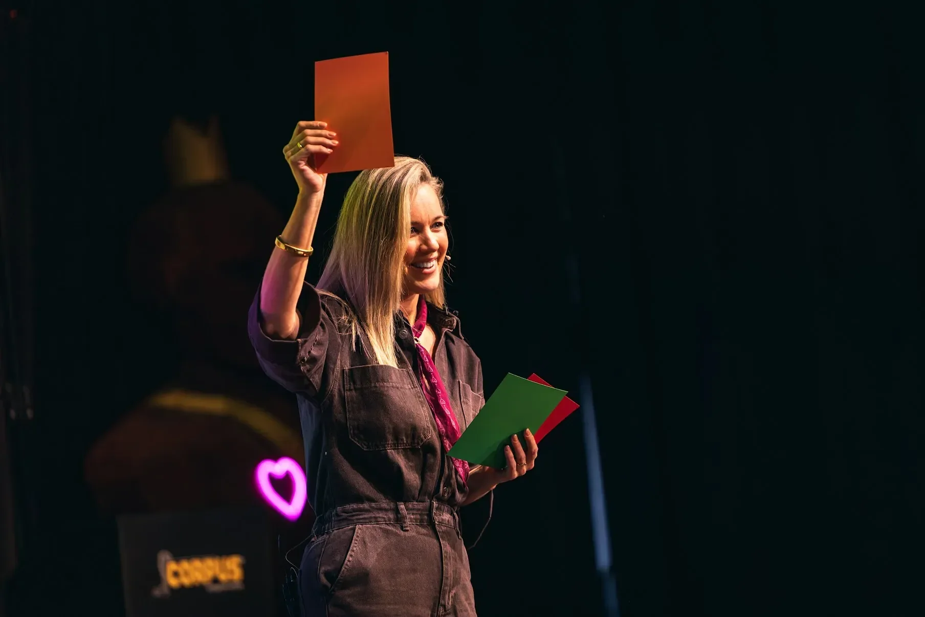 Alies Tax geeft een interactieve training op een podium en houdt een oranje kaart omhoog.